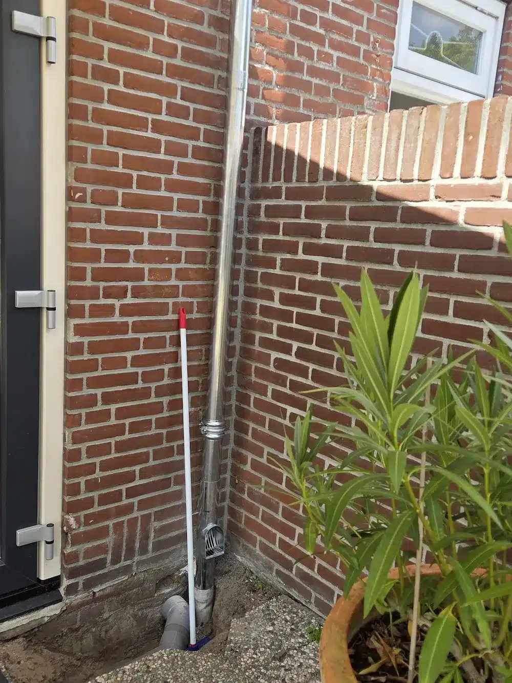 Hemelwaterafvoer met bladvanger aangesloten op de riolering naast de voordeur