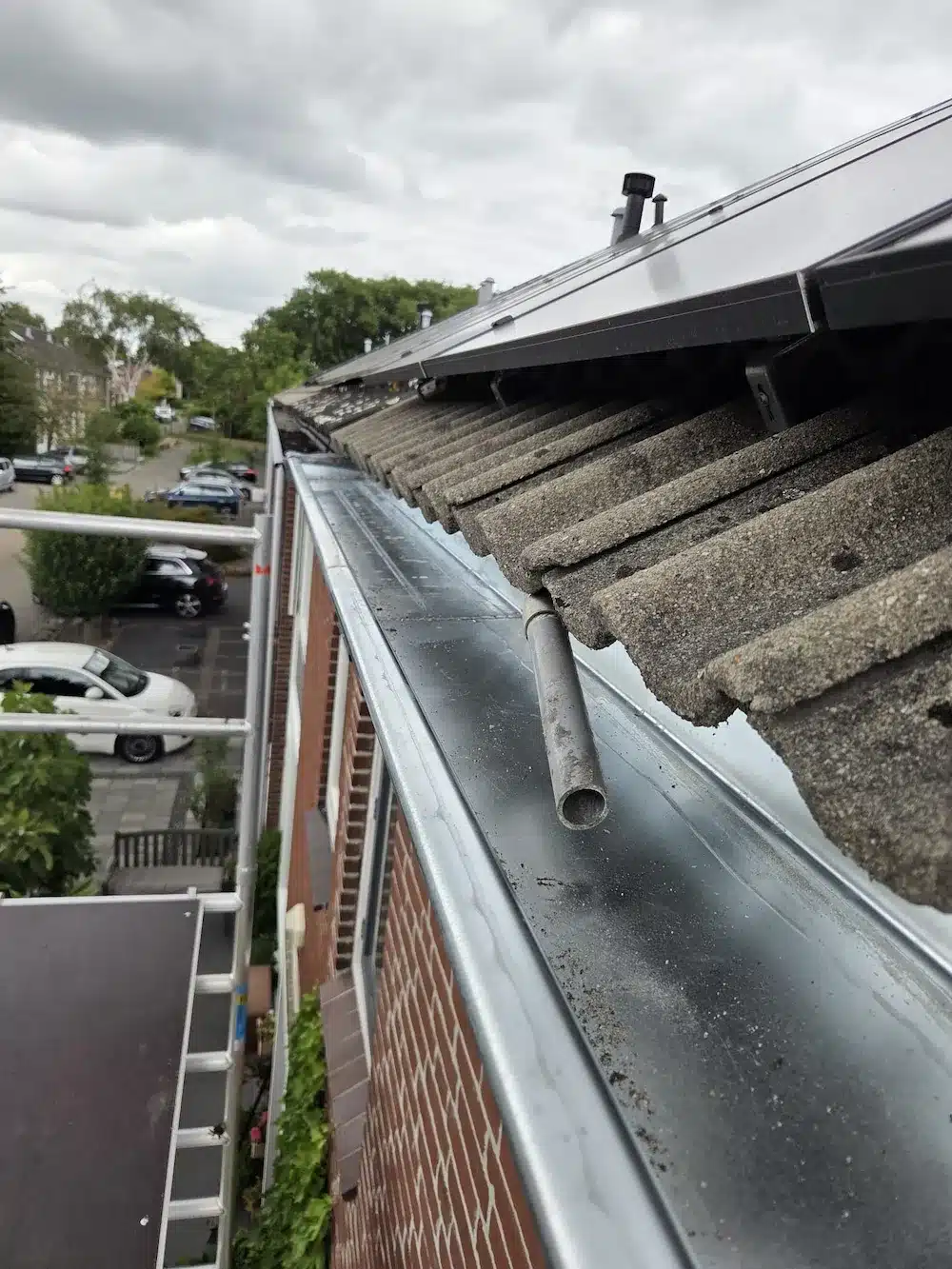 Nieuwe dakgoot met overloop onder de zonnepanelen op het hoofddak