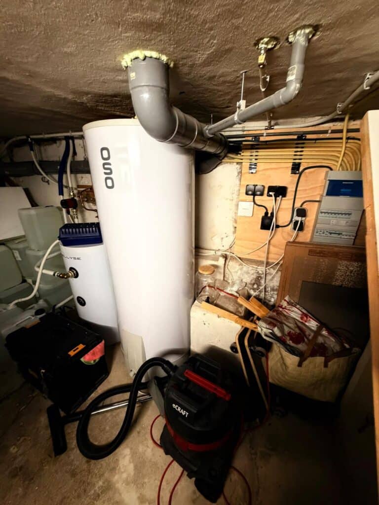 OSO boiler met grijze afvoerleiding door het plafond naast de groepenkast